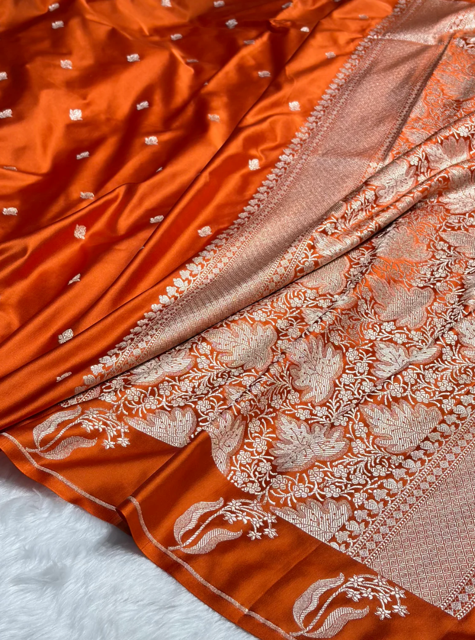 Close-up of an orange fabric with intricate white embroidery on a white background