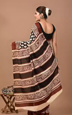 Woman wearing a traditional saree with a brown and beige pattern on a plain background