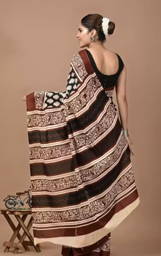 Woman wearing a traditional saree with a brown and beige pattern on a plain background