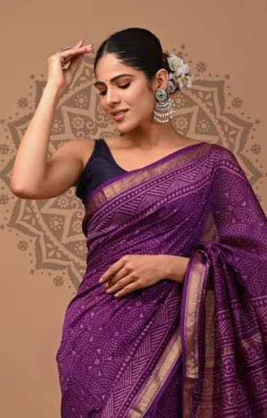 Woman wearing a purple saree with a decorative background