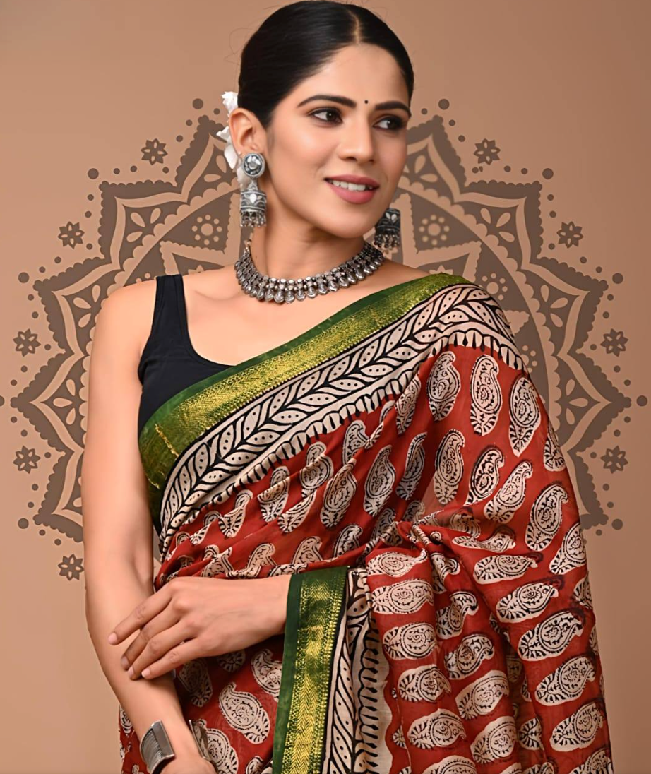 Woman wearing a traditional saree with intricate patterns against a decorative background
