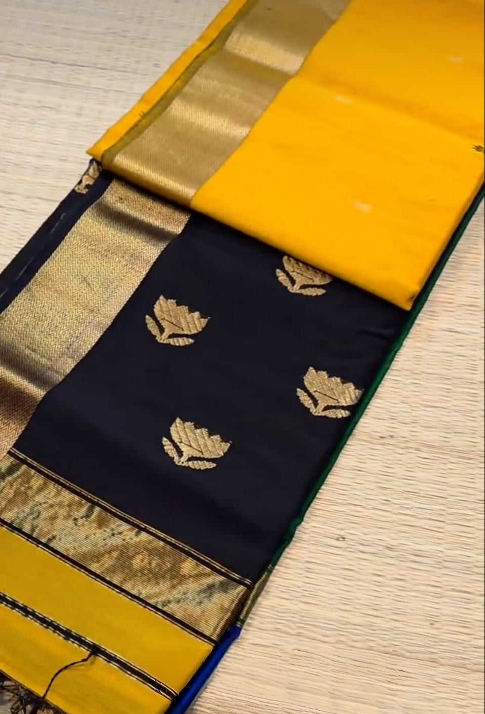 Saree with black and gold patterns on a wooden surface