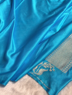 Close-up of a blue fabric with intricate silver patterns on a white background