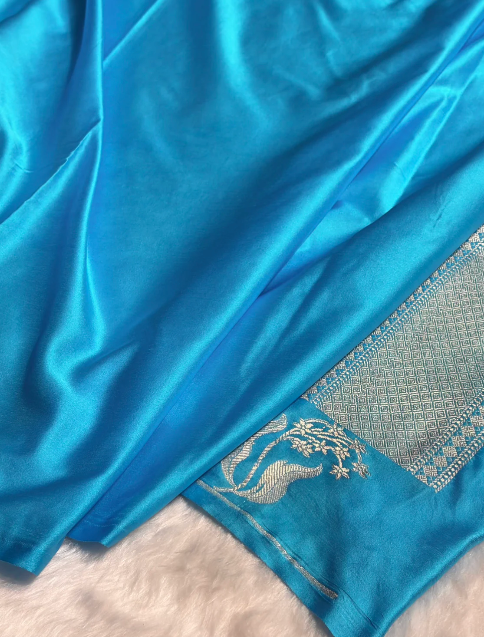 Close-up of a blue fabric with intricate silver patterns on a white background