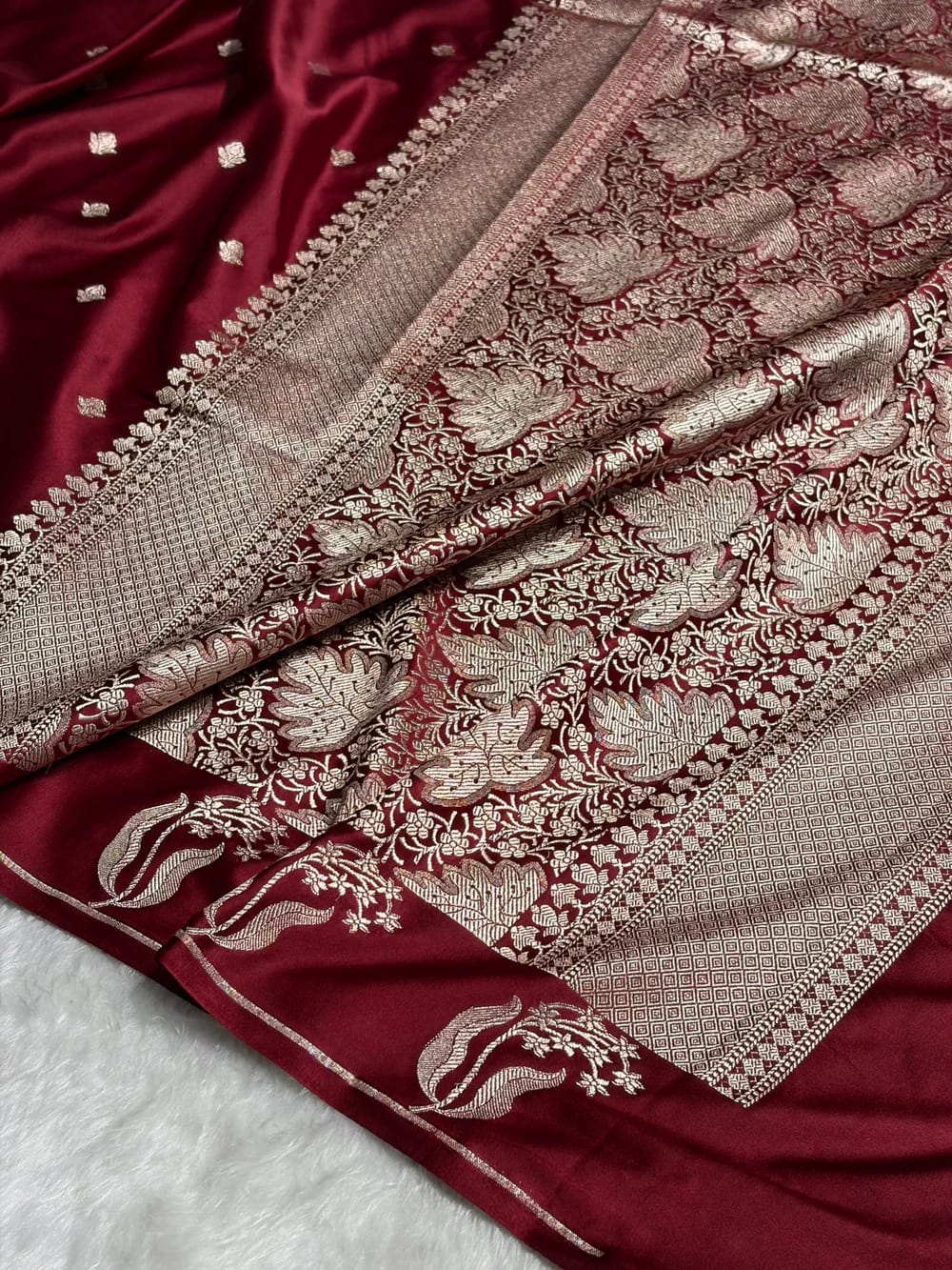 Maroon saree with intricate gold embroidery on a white background