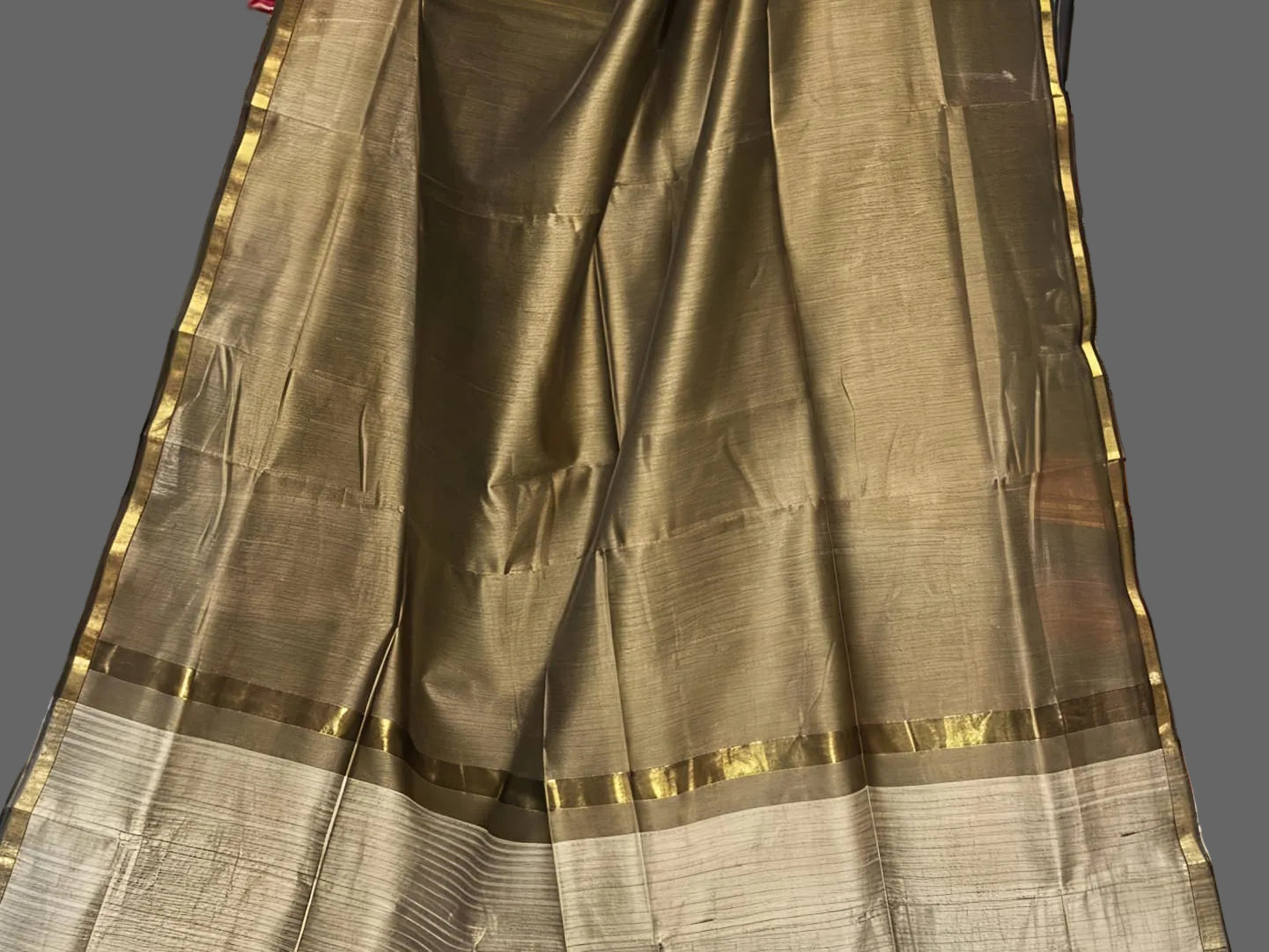Brown saree with gold border on a gray background