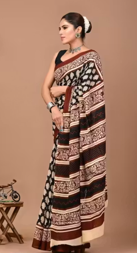 Woman wearing a patterned saree against a beige background