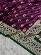 Purple saree with intricate white and green border on a textured surface