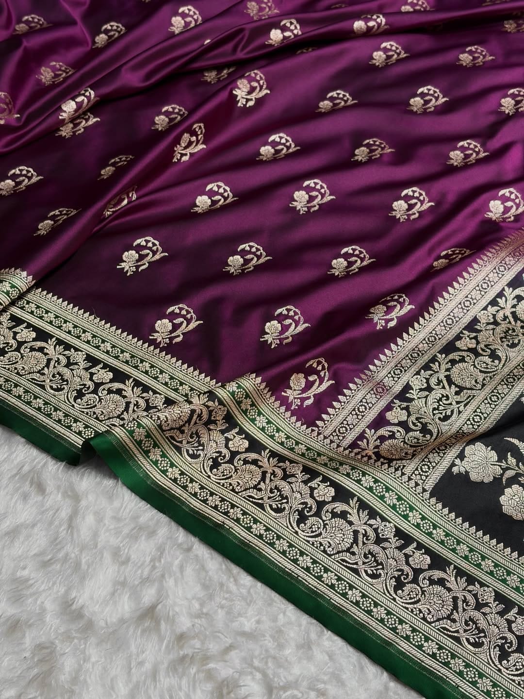 Purple saree with intricate white and green border on a textured surface