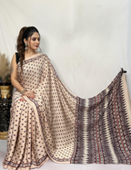 Woman wearing a beige saree with black patterns on a white background