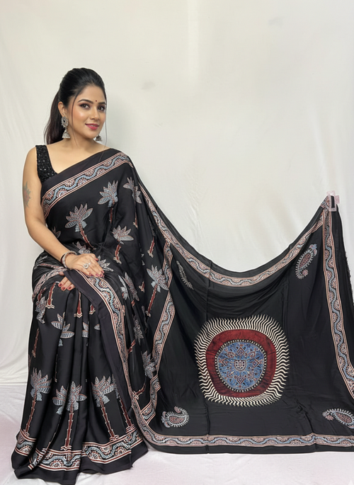 Woman wearing a black saree with floral patterns on a white background