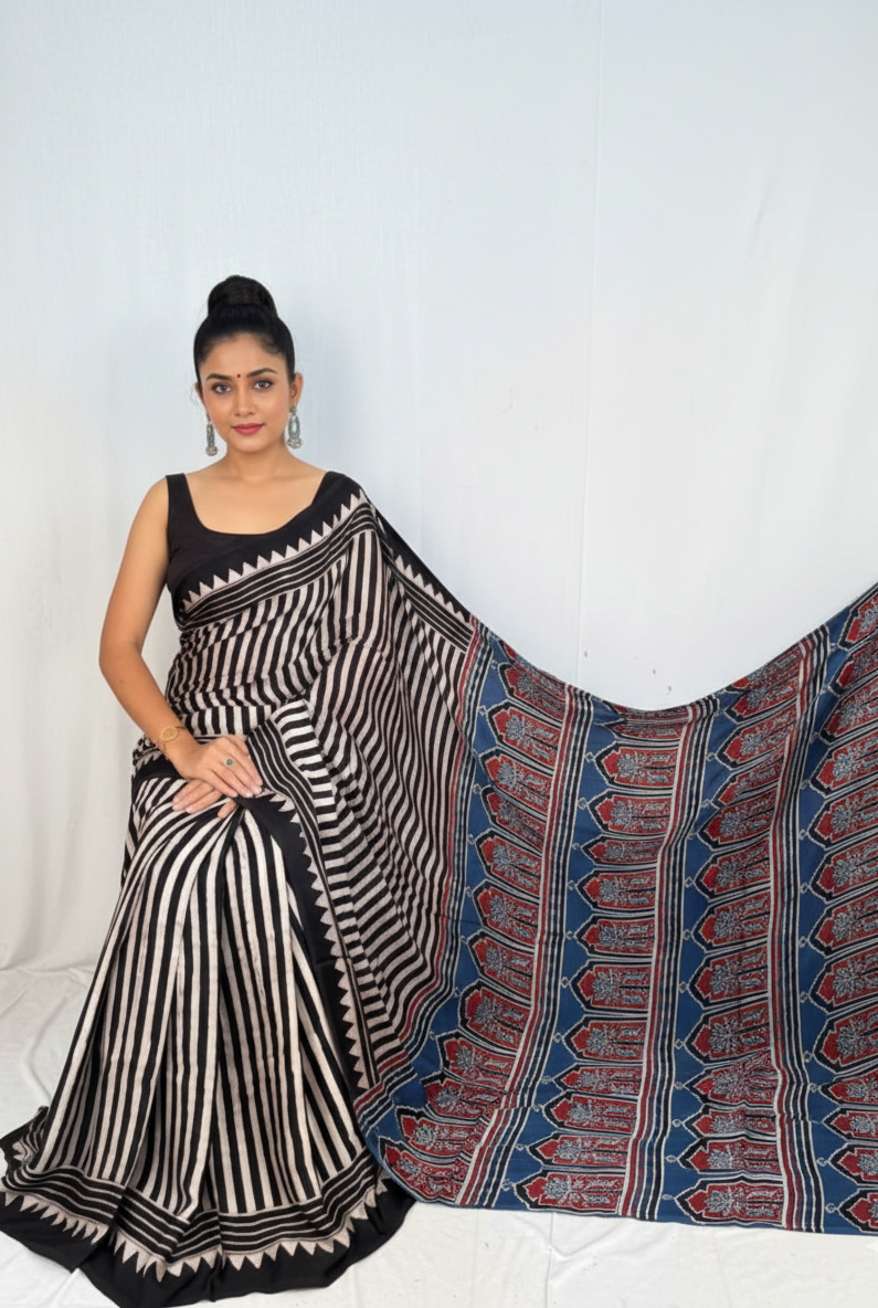 Woman wearing a black and white patterned saree with a blue and red border on a white background