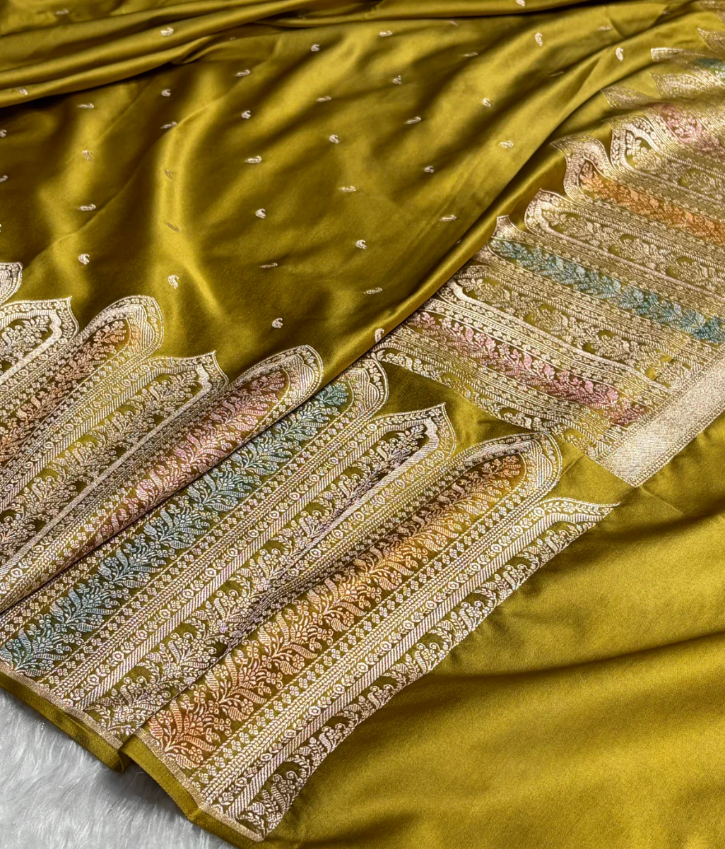 Green saree with intricate gold and multicolor embroidery on a light gray background