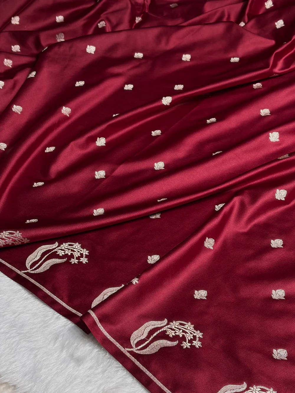 Maroon fabric with white floral embroidery on a white background