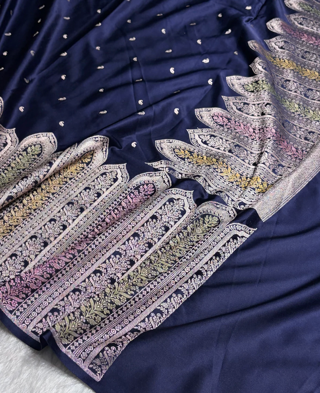 Navy blue fabric with intricate white and multicolor embroidery