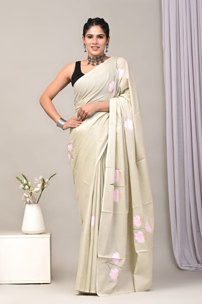 Woman wearing a light-colored saree with pink floral patterns against a neutral background