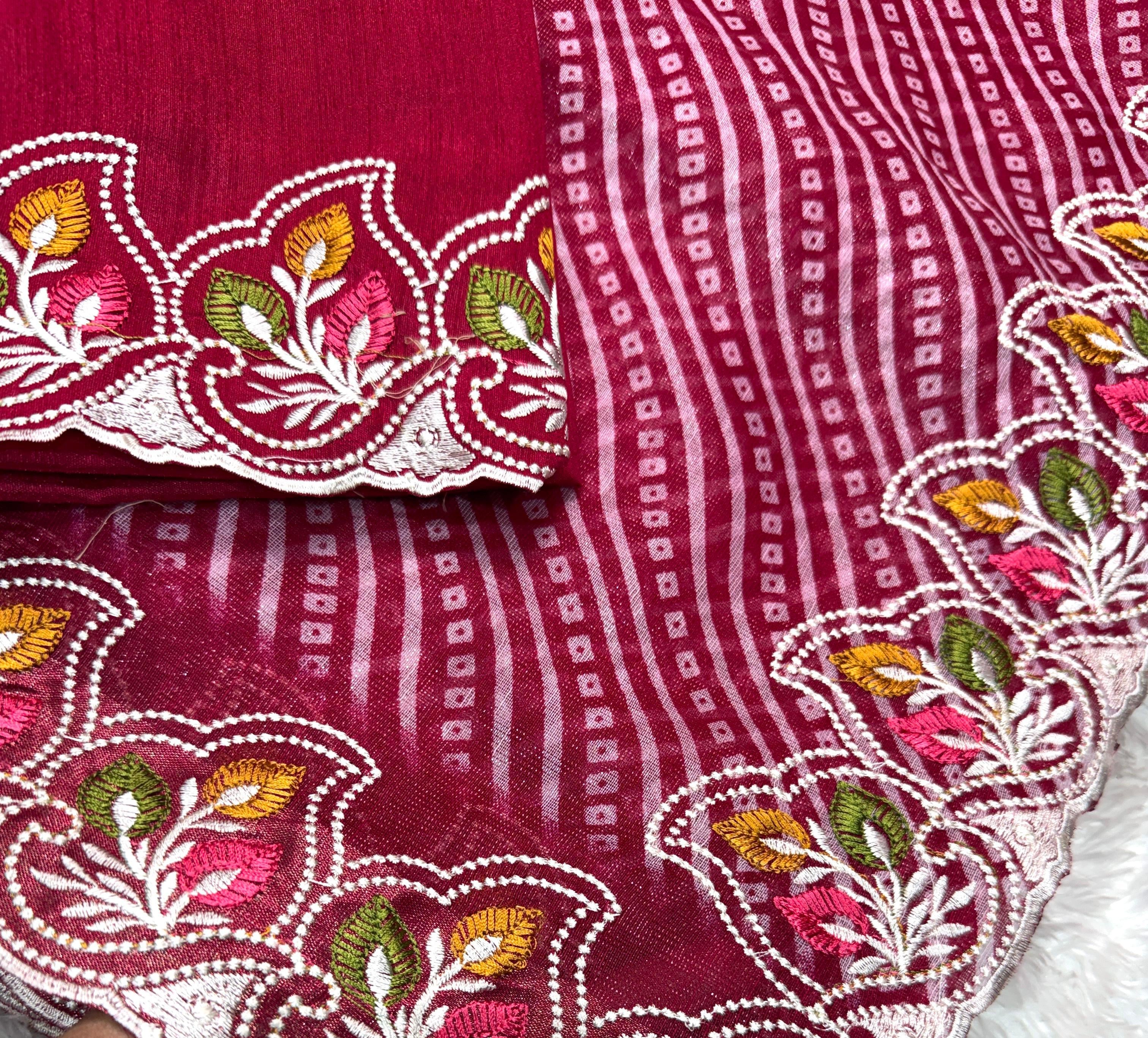 Red fabric with intricate white, green, and pink embroidery held by a hand.
