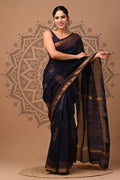 Woman wearing a dark blue saree with gold patterns on a beige background