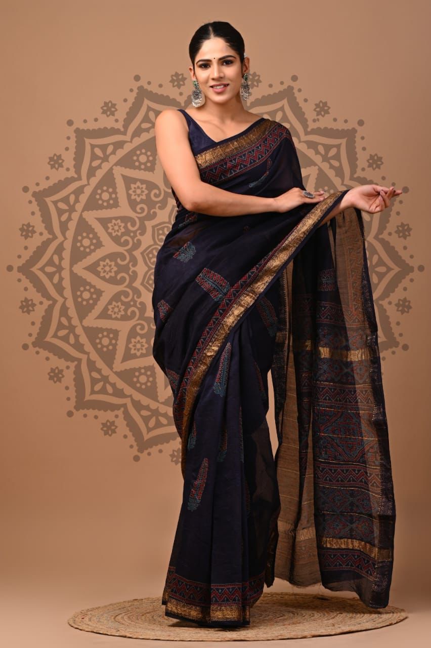 Woman wearing a dark blue saree with gold patterns on a beige background