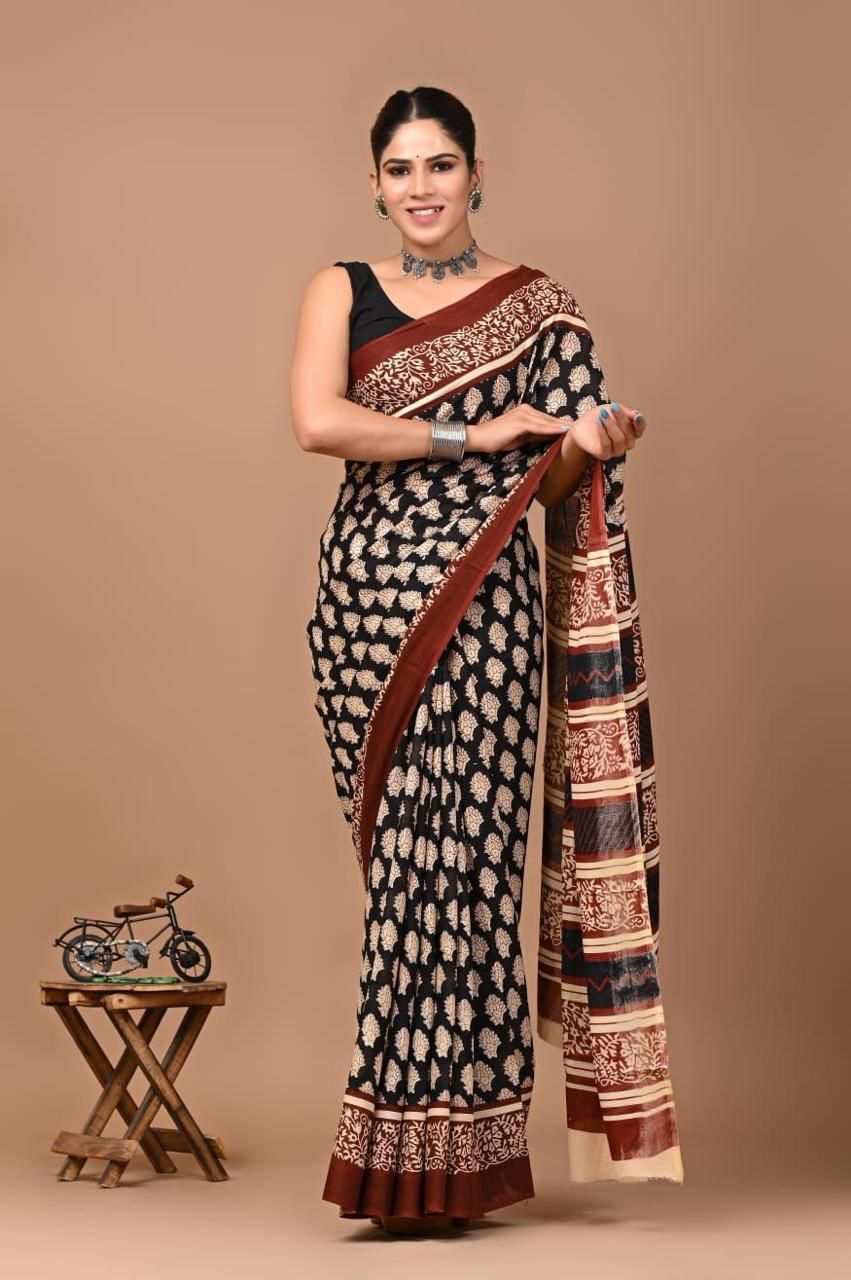 Woman wearing a black and white patterned saree with a brown border on a beige background