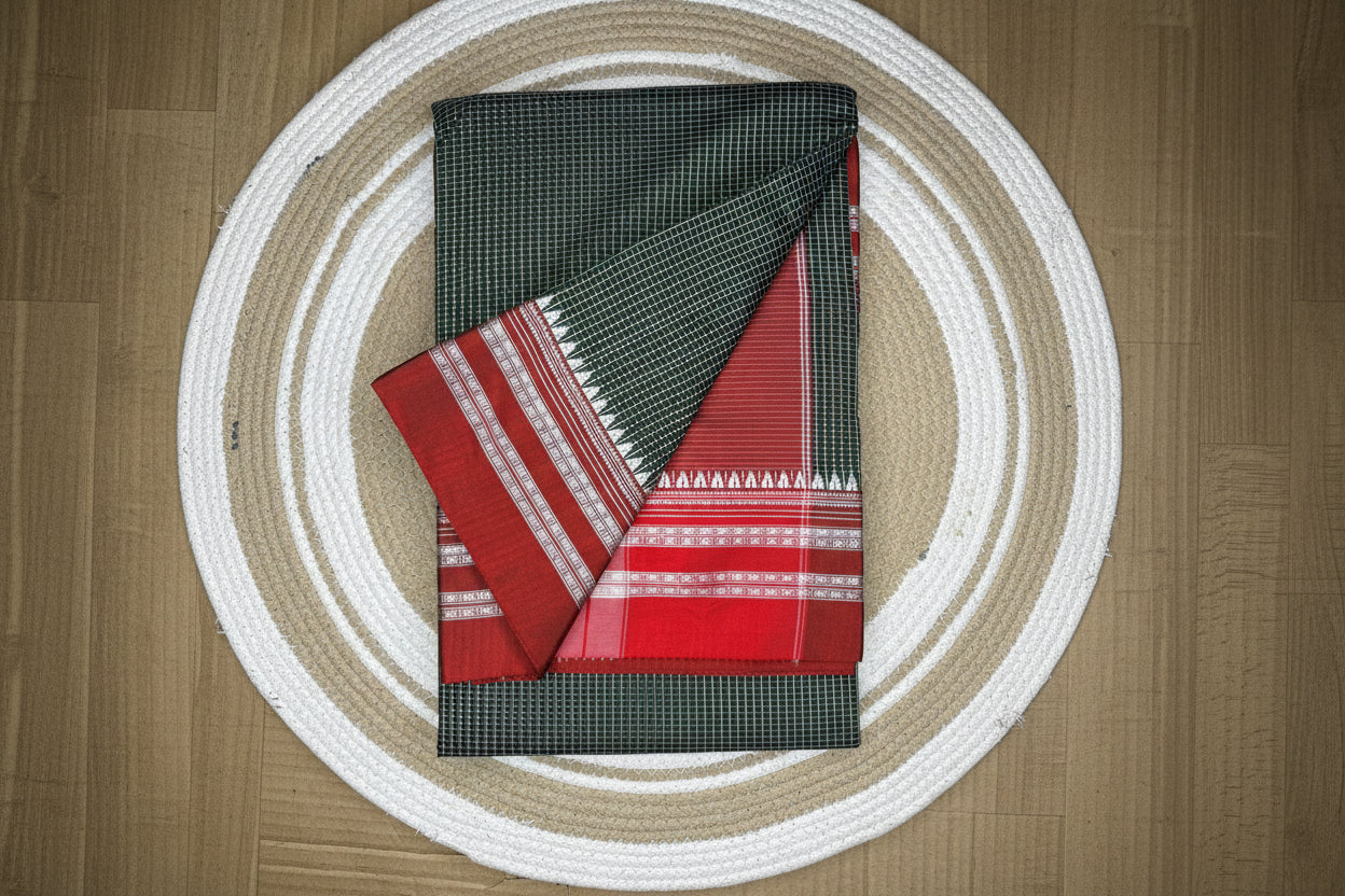 Two folded fabrics, one red with patterns and the other black with a grid pattern, on a circular woven mat.