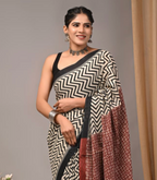Woman wearing a black and white patterned saree with a plain background