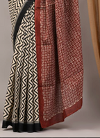 Two patterned scarves, one with black and white zigzag design and the other with red and white floral design, draped over a neutral background.