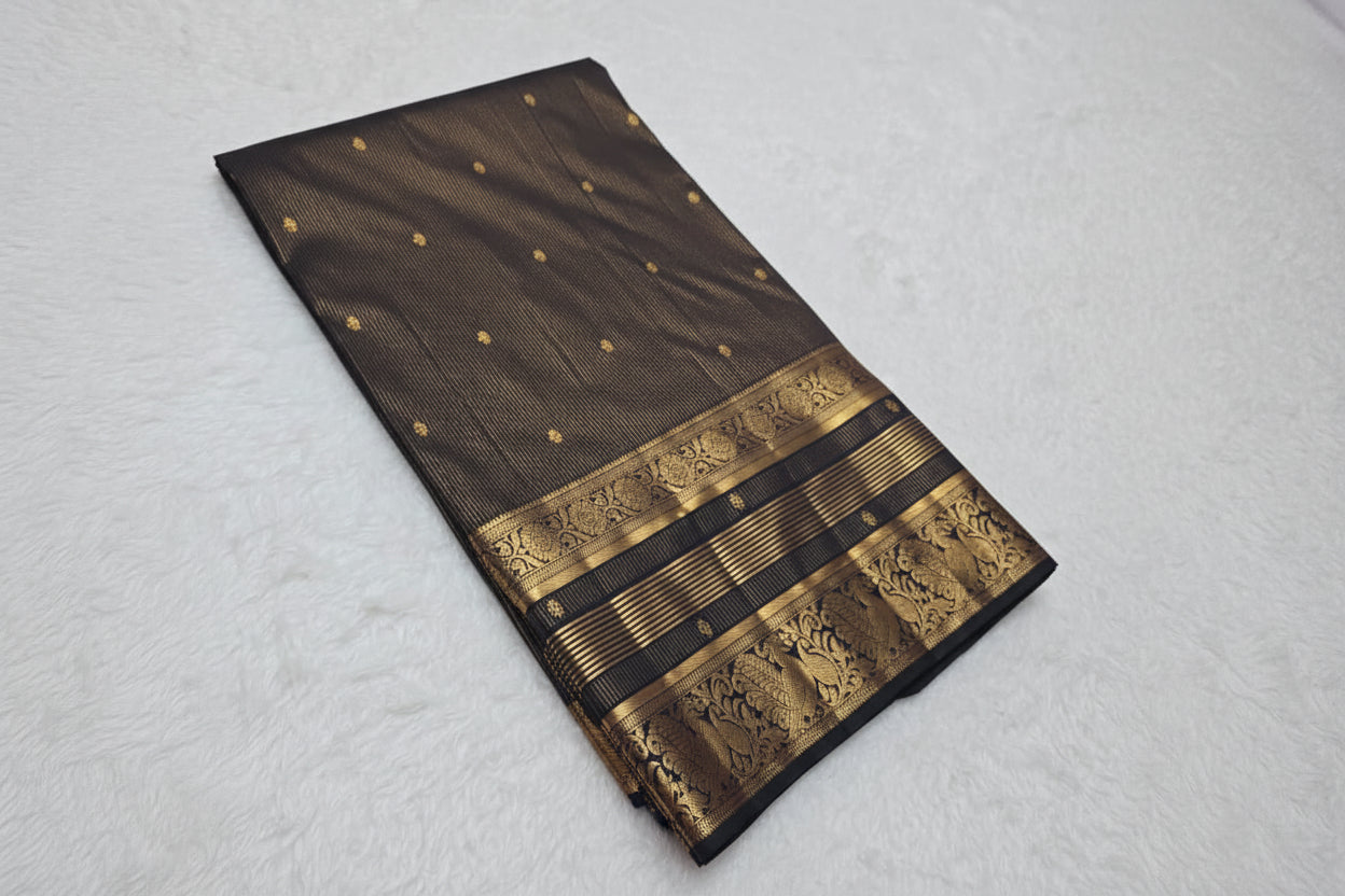 Black saree with gold patterns on a white surface with flowers in the background