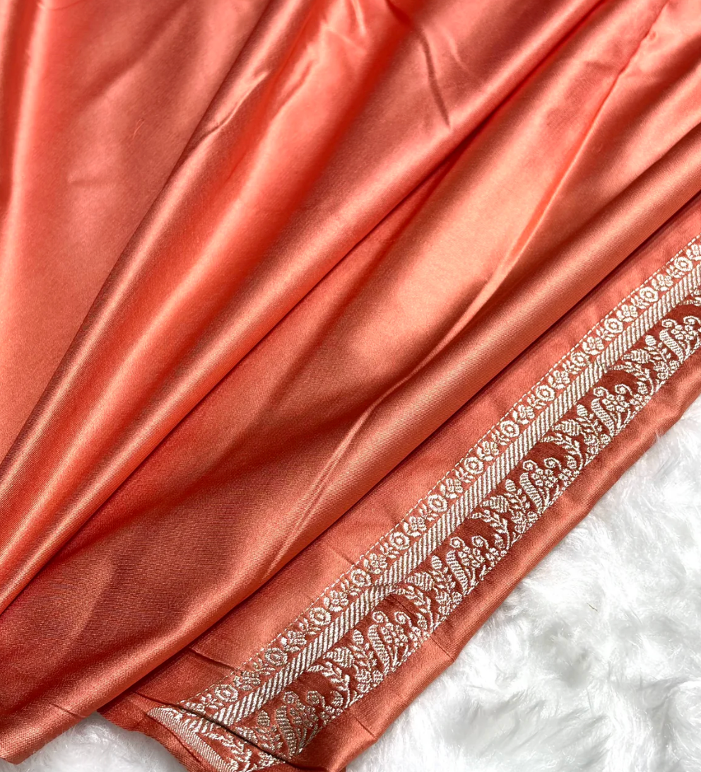 Coral pink fabric with intricate white embroidery on a white background