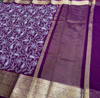 Purple saree with white floral patterns on a red and green checkered floor.