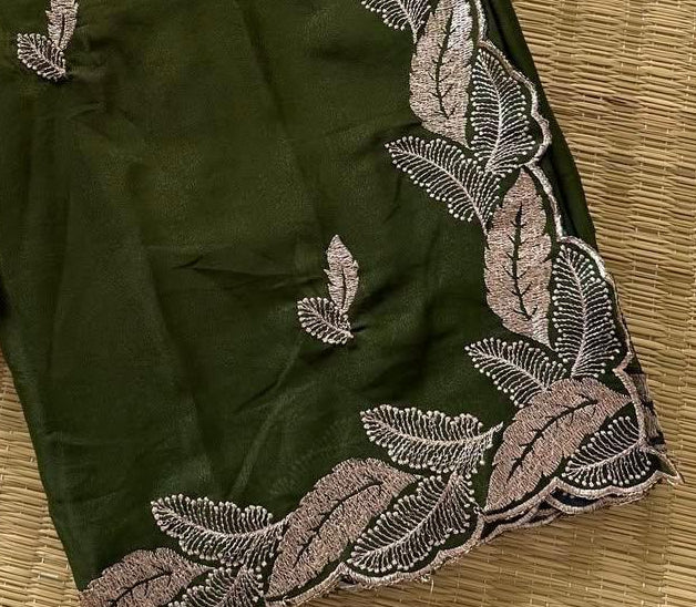 Green saree with floral embroidery on a textured surface