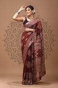 Woman wearing a maroon saree with a pattern on a beige background