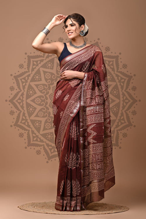 Woman wearing a maroon saree with a pattern on a beige background