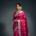 Pink saree with white flower patterns on a light blue background
