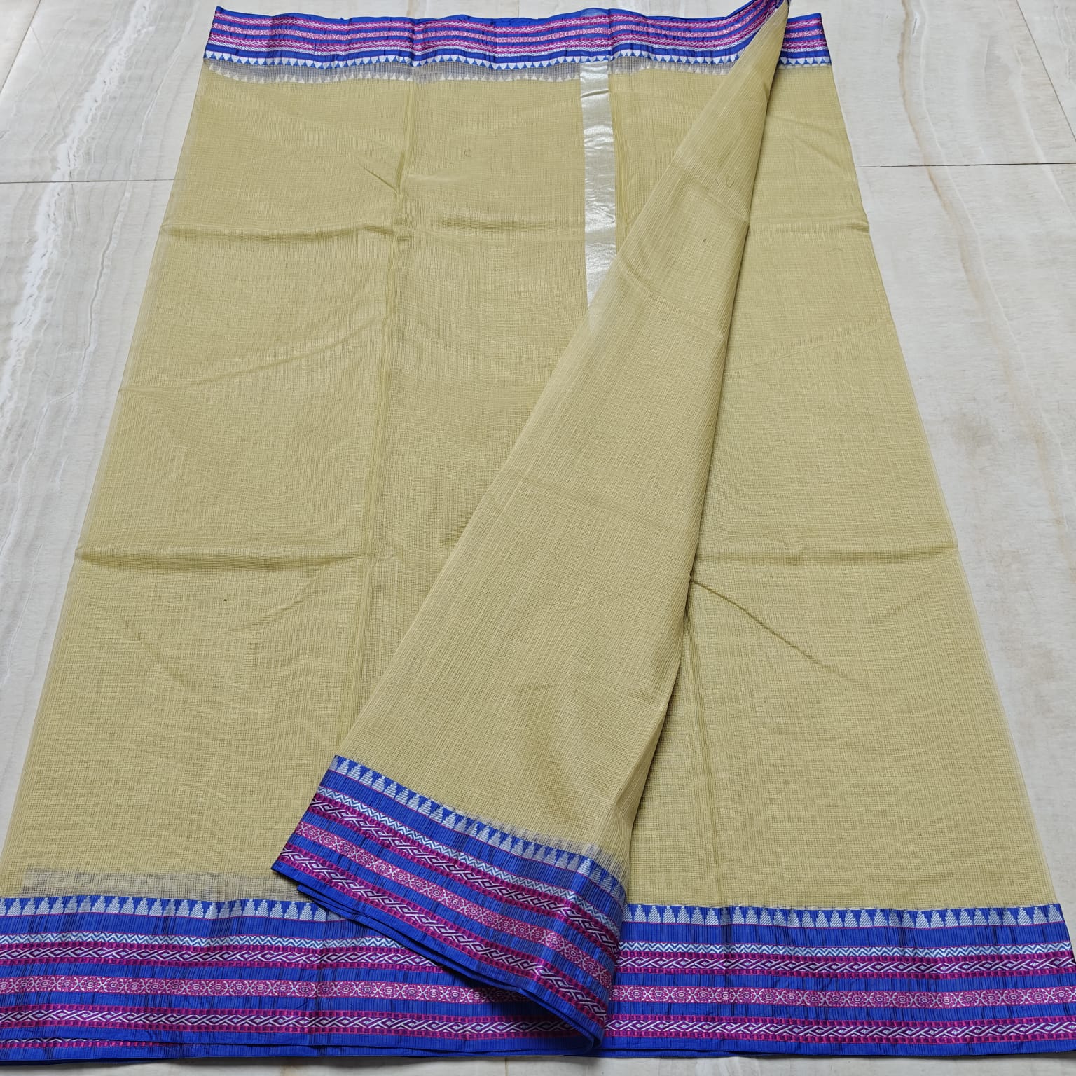 Beige saree with blue and purple border on a light gray background