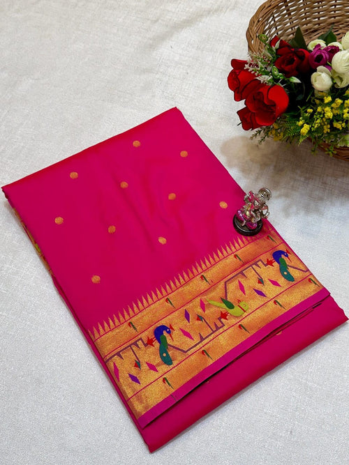 Pink saree with gold and multicolor border on a white surface with flowers and a basket.