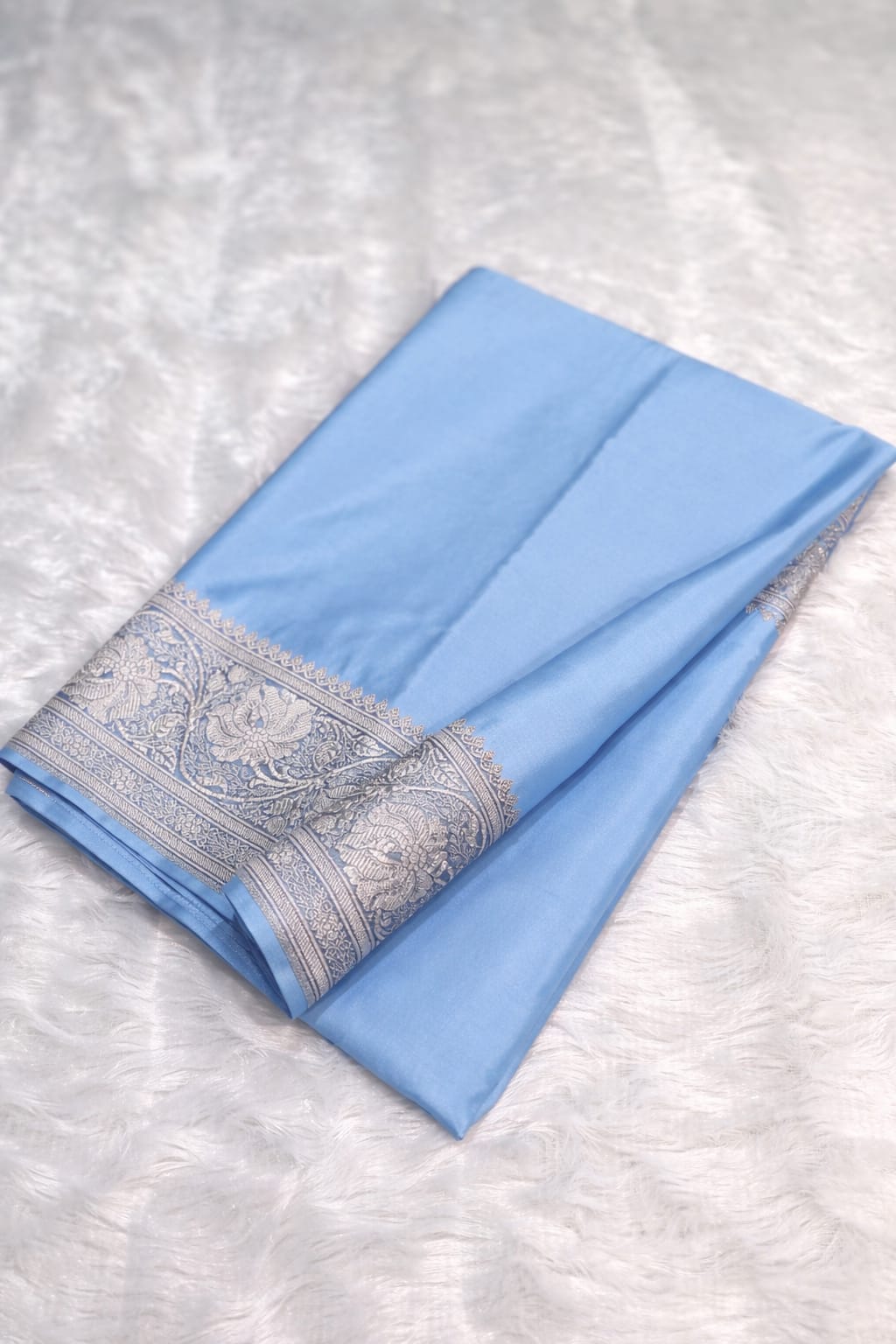 Light blue fabric with silver border on a textured white background