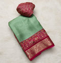 Green and red saree with floral decorations on a white background