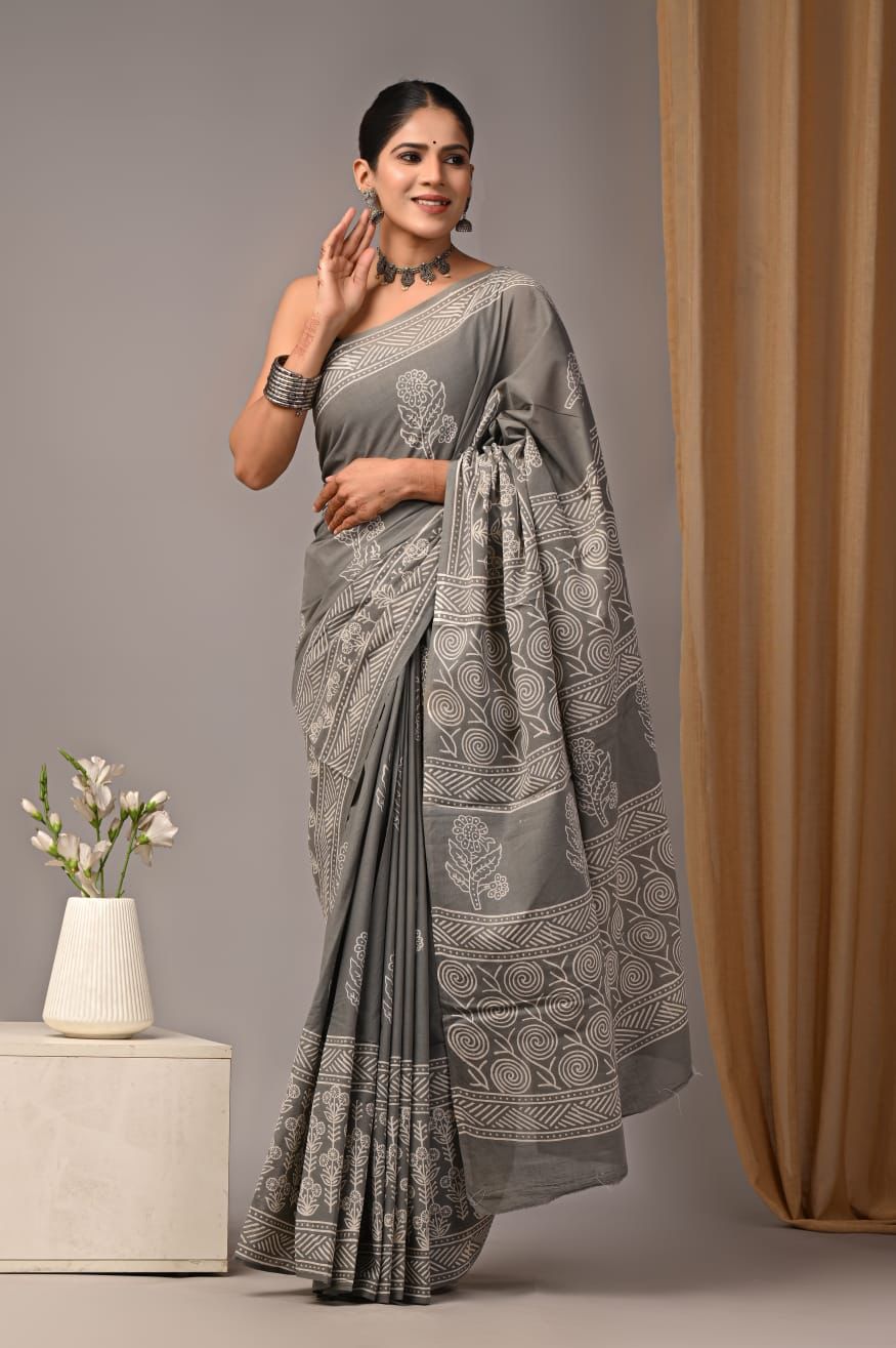 Woman wearing a gray saree with a subtle pattern, standing against a neutral background.