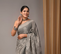 Woman wearing a gray saree with a subtle pattern against a plain background