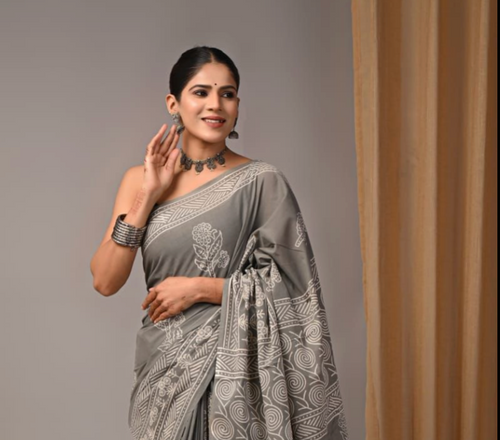Woman wearing a gray saree with a subtle pattern against a plain background