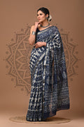 Woman wearing a blue and white patterned saree on a brown background