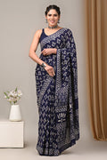 Woman wearing a navy blue saree with white patterns against a neutral background