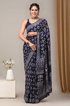 Woman wearing a navy blue saree with white patterns against a neutral background