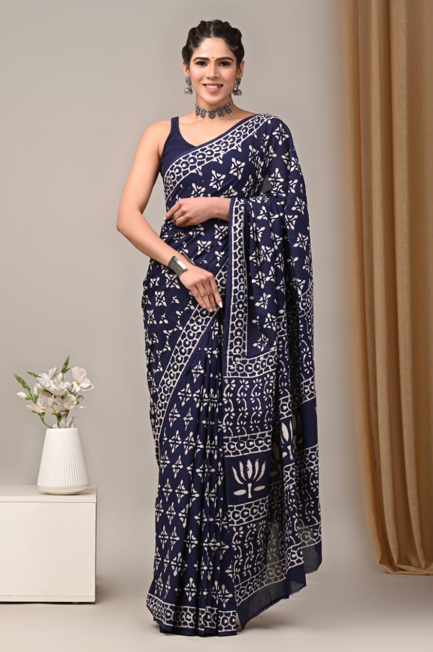 Woman wearing a navy blue saree with white patterns against a neutral background