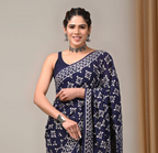 Woman wearing a navy blue saree with white patterns against a neutral background