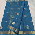 Blue saree with floral patterns and a gold border on a light gray background