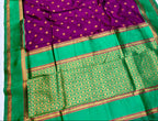 Purple saree with gold polka dots and green border on a white background