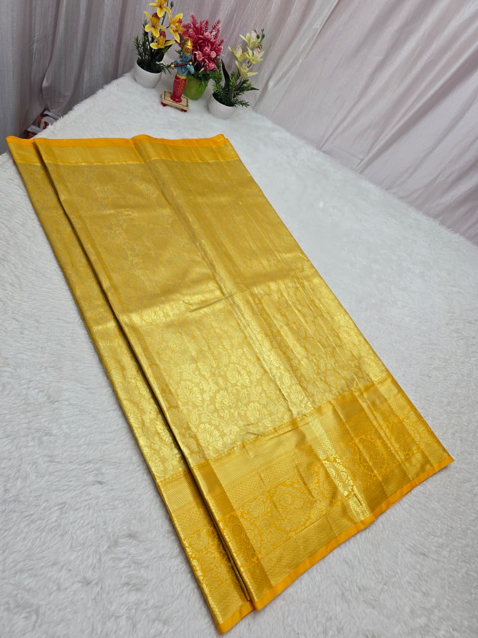 Gold fabric on a white surface with decorative items in the background