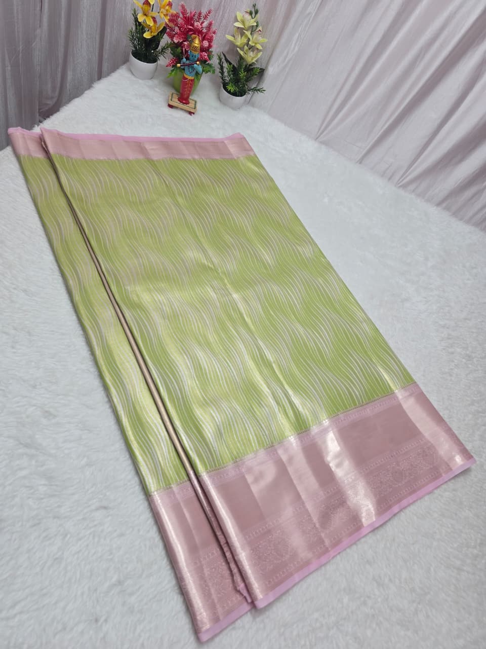 Green and pink fabric on a white tablecloth with decorative items in the background